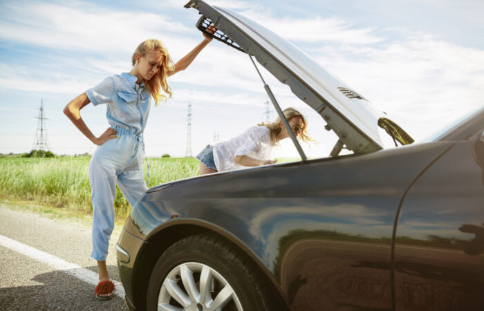 The young lesbian's couple broke down the car while traveling on the way to rest. Trying to fix the broken by their own or should hitchhike, getting nervous. Relationship, troubles on the road, vacation.